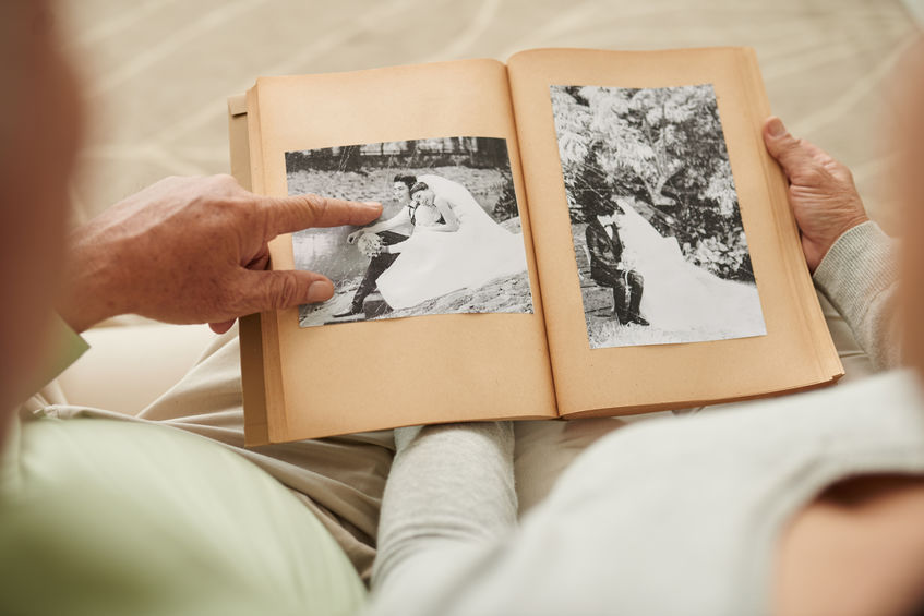 A senior man showing his wedding album and remembering his late wife